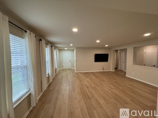 A spacious room with wooden flooring and a flat-screen TV mounted on the wall.