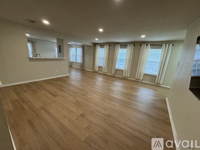 A spacious room with wooden flooring and large windows.