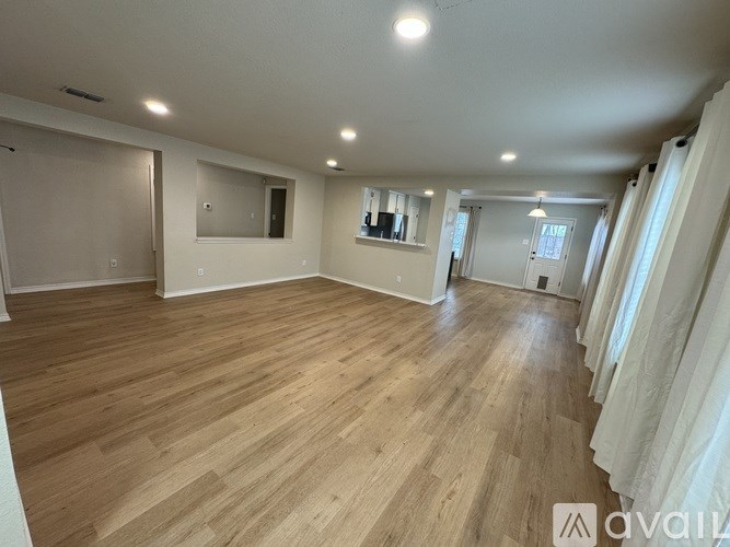 A spacious room with wooden flooring and a large window.