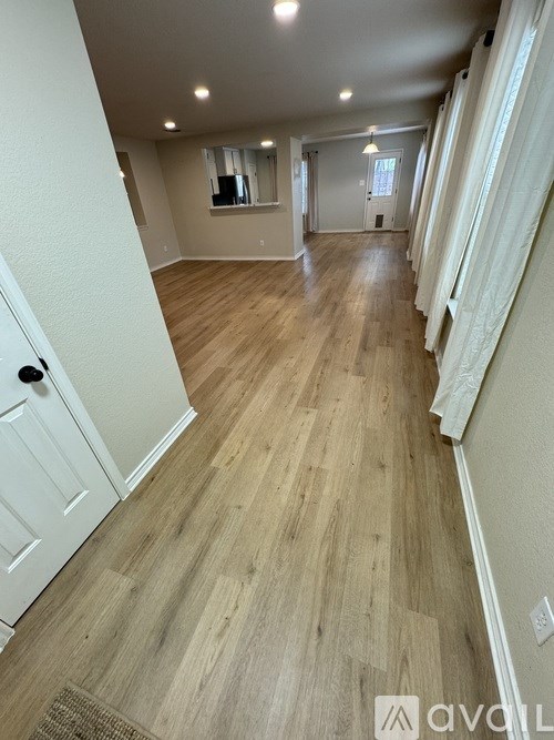 A long hallway with wood floors and white walls.