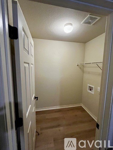 A small, empty room with a door on the left and a shelf on the right.