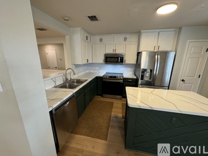 A kitchen with white cabinets and a green island.