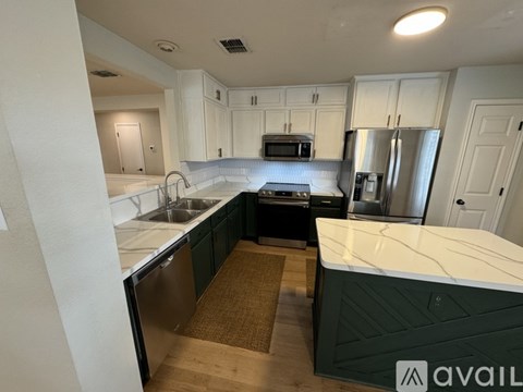 A kitchen with white cabinets and a green island.