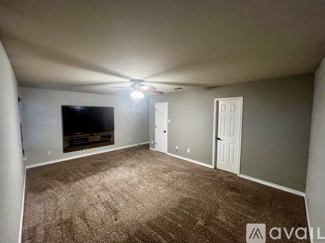 A living room with a flat screen TV and carpeted floor.