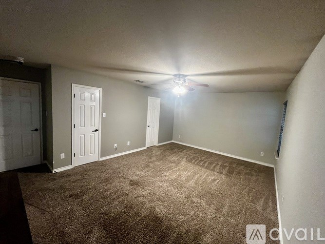 A room with a carpeted floor and a ceiling fan with a light on.