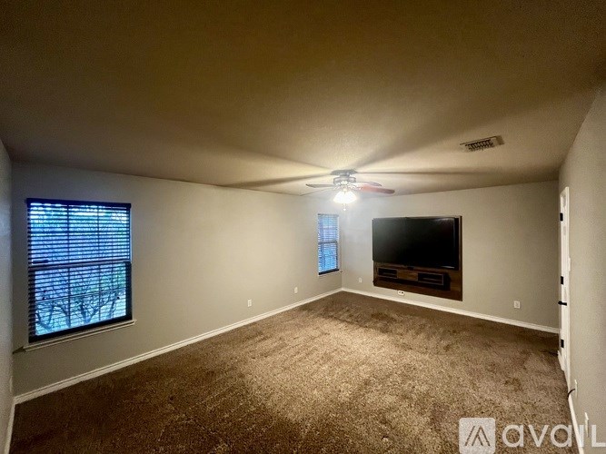 A room with a ceiling fan and a flat screen TV mounted on the wall.