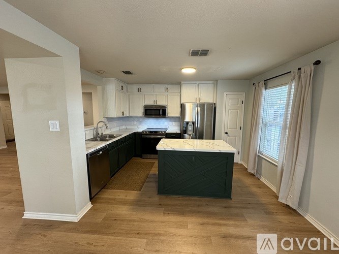 A kitchen with white cabinets and a wooden floor.