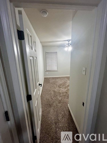 A hallway with carpeted flooring and white walls.
