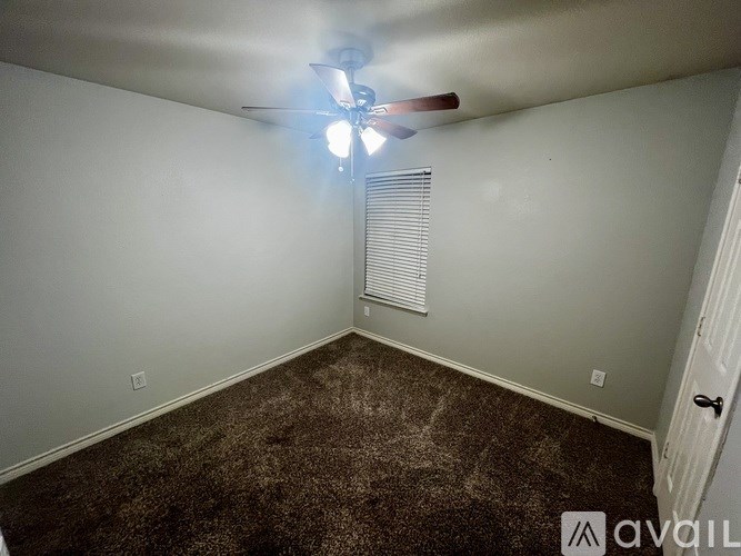 A room with a ceiling fan and a window with blinds.