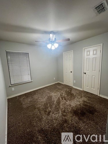 A room with a carpeted floor and a ceiling fan.