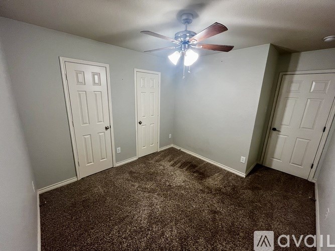 A room with a carpeted floor and a ceiling fan.