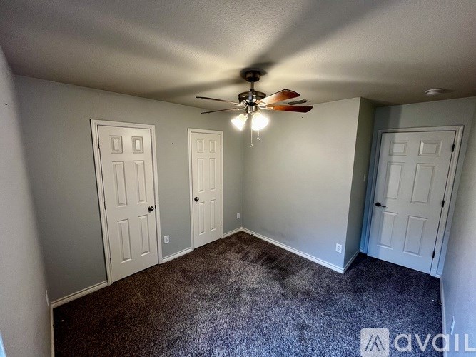 A room with a ceiling fan and three doors.