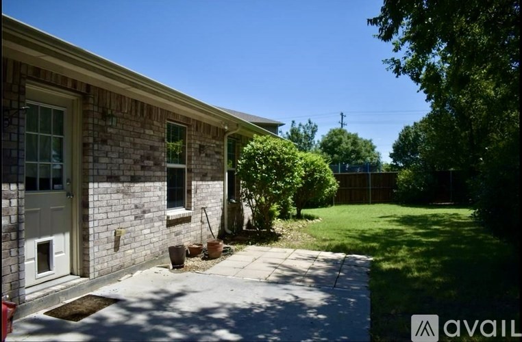 A house with a white door and windows is surrounded by greenery.