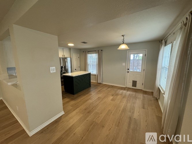 A room with wooden floors and white walls, with a window on the right side.