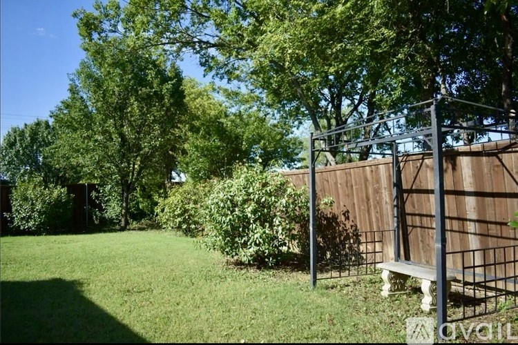 A backyard with a bench and a fence.