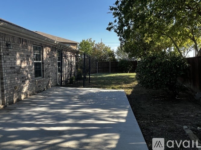 A sunny day at a house with a fence and a tree.