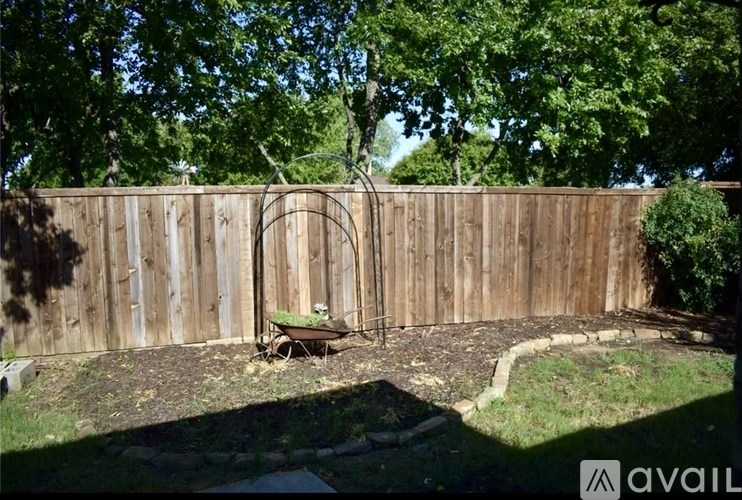 A backyard with a wooden fence and a garden hose.