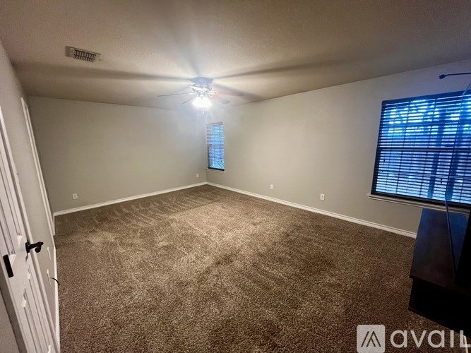 A room with carpeted floor, a ceiling fan, and a window with blinds.
