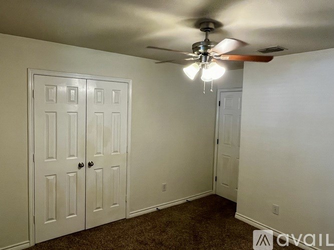 A room with a ceiling fan and two doors.