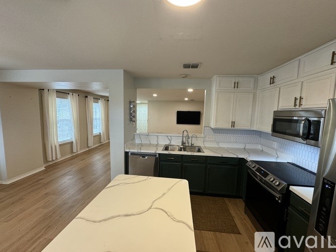 A kitchen with white cabinets and a wooden floor.