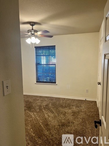 A room with a ceiling fan and a window with blinds.