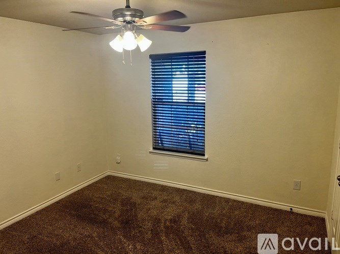 A room with a ceiling fan and a window with blinds.