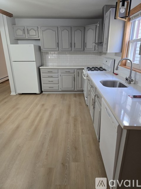 A kitchen with white appliances and wooden floors.