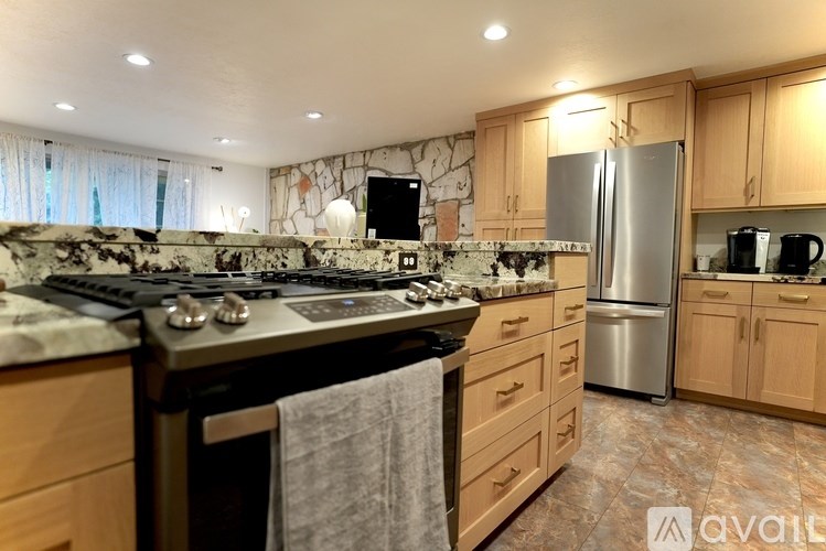 A kitchen with wooden cabinets and a marble backsplash.