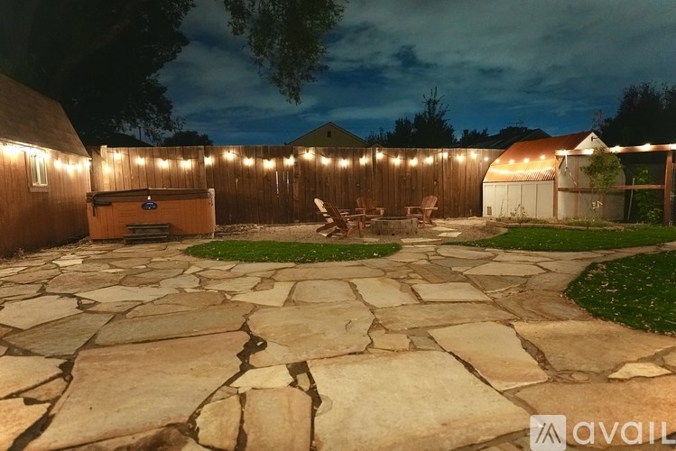 A backyard with a stone patio and string lights.