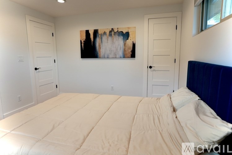 A bedroom with a large bed and a painting on the wall.