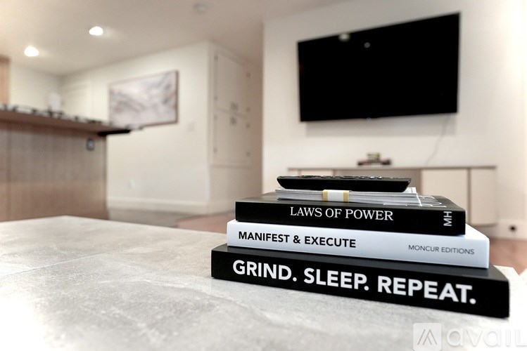 Three books stacked on top of each other with the top one reading Grind Sleep Repeat.