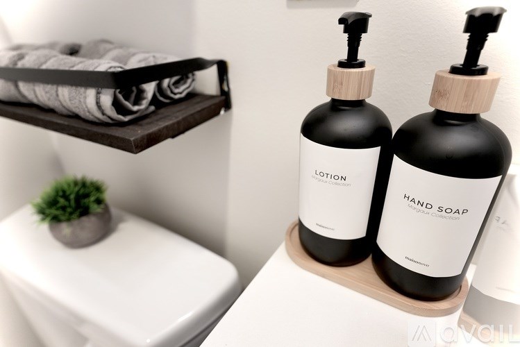 Two bottles of hand soap on a shelf in a bathroom.