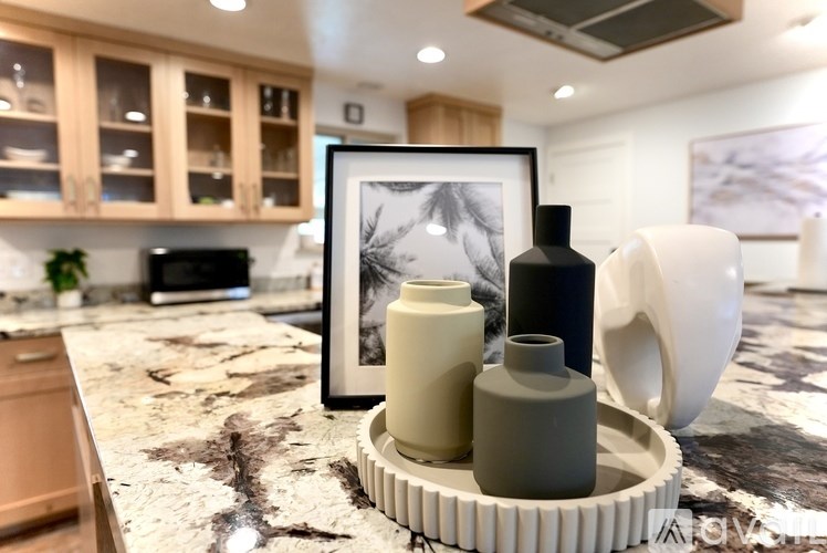 A kitchen counter with a picture frame, a bottle of oil, and a container of paint.