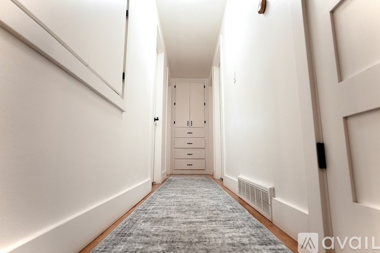 A hallway with a carpeted floor and a series of doors on the right side.