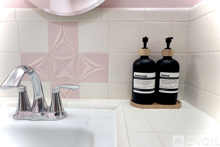 Two bottles of hand soap and lotion on a tray in a bathroom.