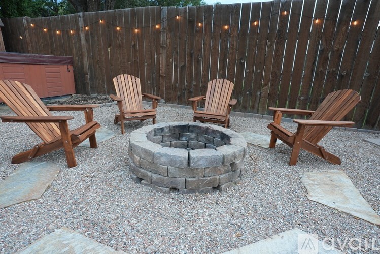 A fire pit surrounded by wooden chairs in a backyard setting.