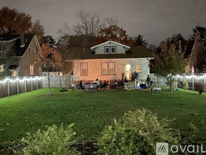 A house with a group of people sitting outside at night.