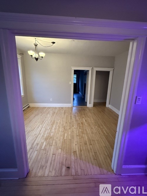 A room with wooden flooring and a chandelier.