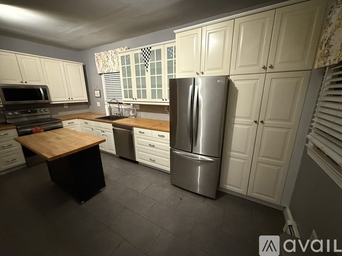 A kitchen with a wooden island and a stainless steel refrigerator.