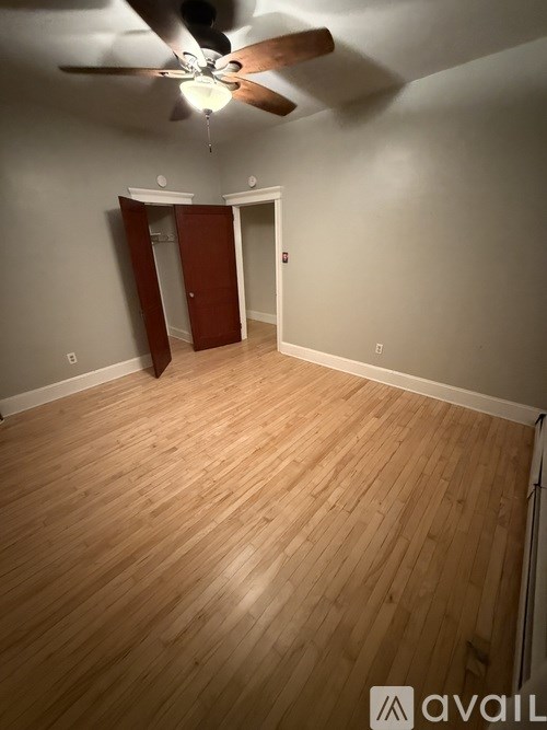 A room with a ceiling fan and wooden flooring.