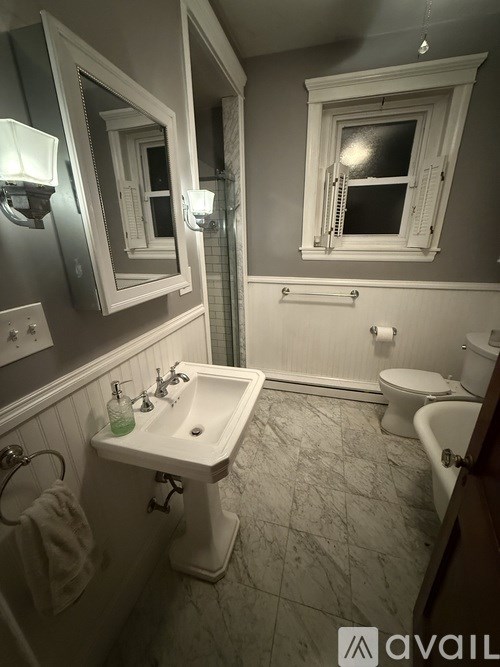 A bathroom with a sink, toilet, and a window.