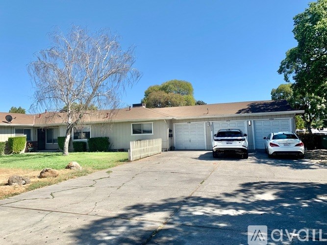 A house with a white garage door and two cars parked inside.