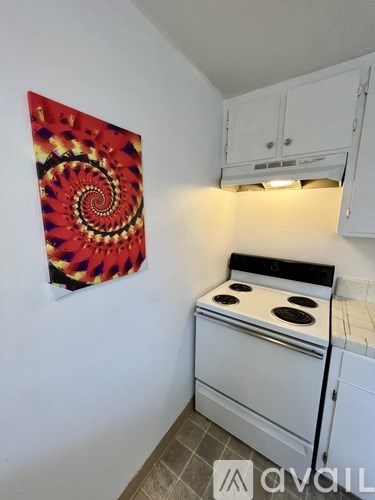 A kitchen with a white stove and a wall hanging picture.