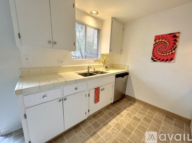 A kitchen with white cabinets and a tiled floor.