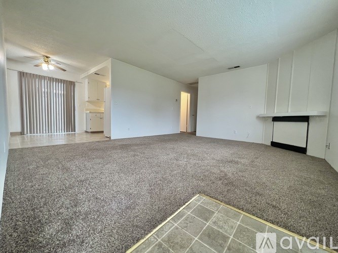 A spacious room with a carpeted floor and a ceiling fan.