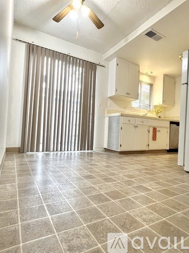 A spacious kitchen with a tiled floor and a ceiling fan.