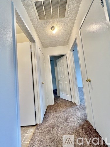 A hallway with white walls and a carpeted floor.