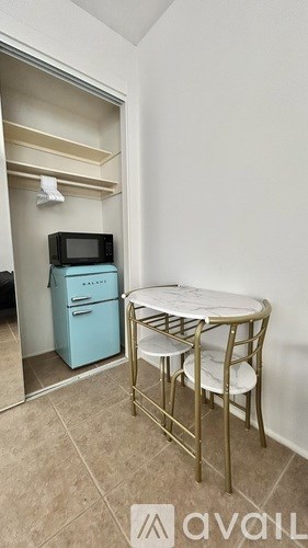 A kitchen area with a table and chairs and a fridge.
