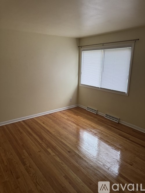 A room with wooden flooring and a window with blinds.