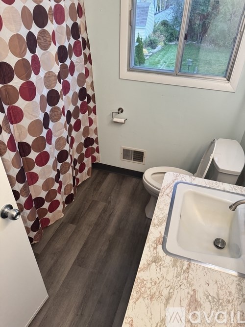 A bathroom with a shower curtain, toilet, and sink.